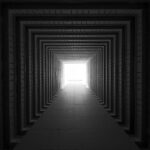 Black and white image of a tunnel-like architecture with sunlight illuminating the end.
